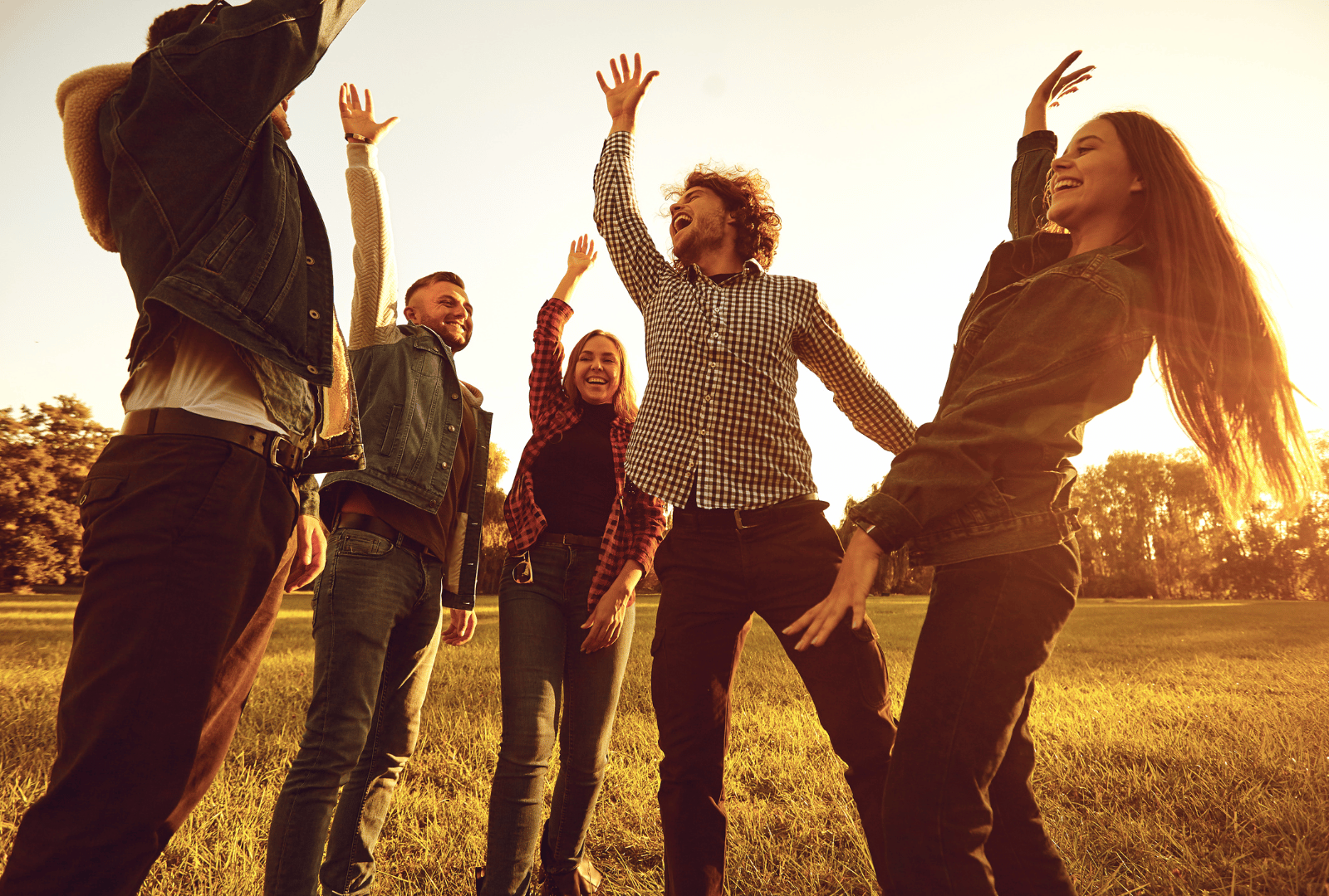 Grupo de personas celebrando al aire libre al atardecer, simbolizando conexión, alegría y energía vital renovada